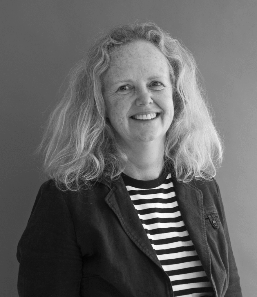 Black and white photograph of a woman looking towards the camera. Her name is Catherine Croft, and she is an Architectural Historian and 20th Century Architecture Conservation Expert